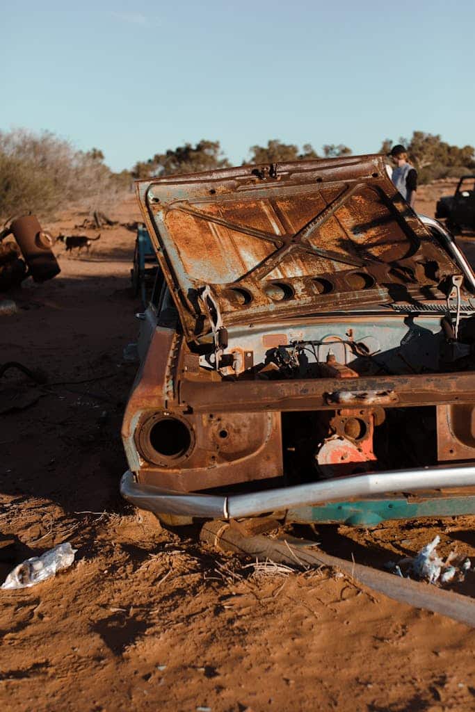 Rusty crushed automobile with damaged details located in desert with dry plants in hot day